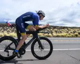 Triathlet auf einem Van Rysel XCR Rennrad, konzentriert auf der Straße, mit trockenem Gras und Vulkanlandschaft im Hintergrund.