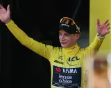 Radfahrer im gelben Trikot der Tour de France winkt jubelnd ins Publikum.