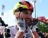 Glückliche Radfahrerin Franziska Koch mit Helm in Deutschlandfarben, die sich die Hände vors Gesicht hält.