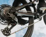 Nahaufnahme einer SRAM Schaltung am Fahrrad. Die Kette läuft über die Kassette, während ein Schuh auf dem Pedal zu sehen ist. Perfekt, um die SRAM Schaltung einzustellen.