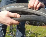 Hände wechseln einen platten Fahrradreifen. Der Reifen ist ein Schwalbe Big Ben.