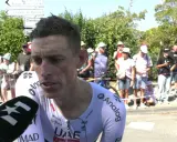 Brandon McNulty, Radfahrer im UAE-Trikot, gibt ein Interview. Im Hintergrund stehen Zuschauer und Straßenschilder.