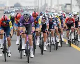 Max Walscheid im violetten Trikot kämpft sich mit anderen Radfahrern durch ein Rennen.