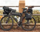 Bereit für die nächste gravel tour: Ein voll beladenes Gravelbike mit Ortlieb-Taschen, Trinkflaschen und sogar Schuhen auf dem Gepäckträger.