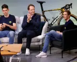 Drei Männer, darunter ein Fahrer von Jumbo-Visma, sitzen auf Sofas vor einem Rennrad.