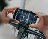 Hände halten Smartphone mit Bosch Flow App Navigation offline. Karte zeigt Route, Distanz und Geschwindigkeit.