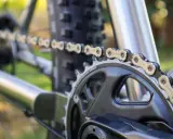 Nahaufnahme einer Fahrradkette, die über ein Kettenblatt läuft. Die Kette zeigt deutliche Gebrauchsspuren, was auf die Shimano Ketten Unterschiede in Bezug auf Haltbarkeit und Leistung hinweist.