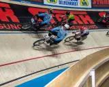 Radfahrer in blauen Trikots kämpfen auf der Bahn. Einer von ihnen könnte der beste Radfahrer der Welt sein, der alles gibt.