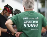 Männer in Radlerkleidung, einer trägt ein grünes T-Shirt mit der Aufschrift "RTFneumarkt.de NEVER STOP RIDING".