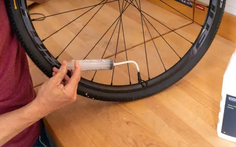 Mit einer Spritze wird Dichtmilch in den Tubeless Reifen gefüllt. So gelingt das tubeless reifen montieren.