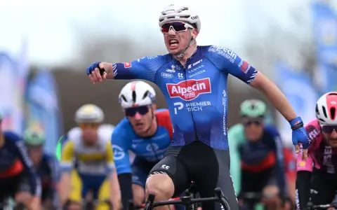 Henri Uhlig jubelt im Radsportrennen, seine Arme ausgestreckt, während er auf dem Rad sitzt.