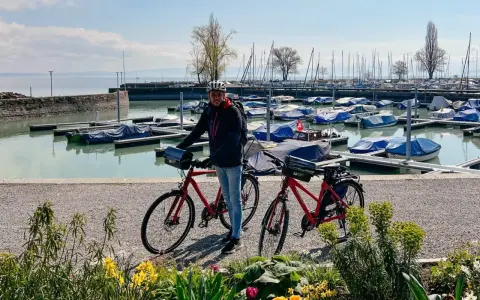Mann mit Rennrad am Bodensee, bereit für die Bodensee Umrundung. Boote im Hafen.