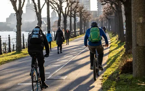 Genießen Sie eine entspannte **Rhein Fahrradtour** entlang des Ufers. Die Sonne wirft lange Schatten auf den Weg.