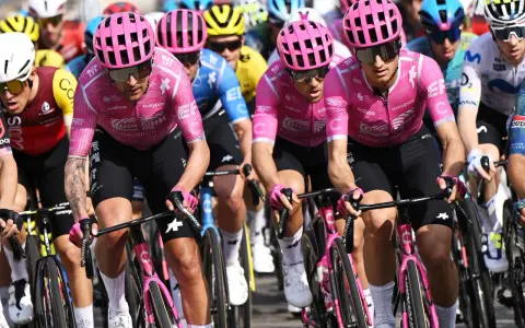 Radfahrer im pinken Trikot mit "Education First Team" Aufdruck, konzentriert auf der Strecke.