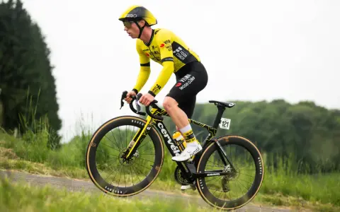 Matthew Brennan im gelben Trikot fährt auf seinem Rennrad durch eine grüne Landschaft.