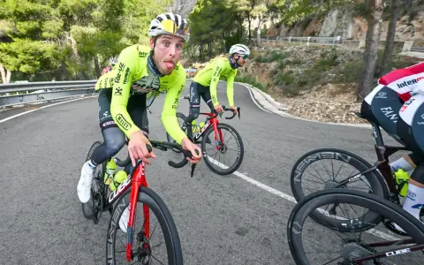Jonas Rutsch zeigt Zunge auf dem Rennrad, während er auf einer kurvigen Bergstraße fährt.
