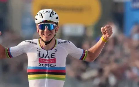 Jubelnder Radfahrer im UAE-Trikot, die Arme erhoben. Sein Erfolg spiegelt sich im hohen Pogacar Gehalt wider.
