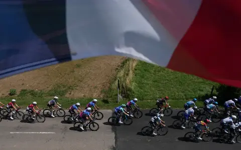 Radfahrer im Peloton, die französische Flagge weht im Wind. Ein spannender Moment am Tour de France Ende.