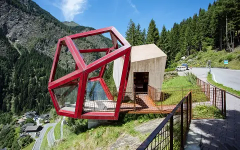 Moderne Architektur am Timmelsjoch. Ein Rennradfahrer genießt die Aussicht auf die Serpentinenstraße.