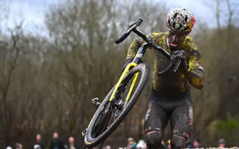 Wout van Aert kämpft sich im Schlamm durch ein hartes Cyclocross-Rennen, sein Körper und Rad sind komplett mit Dreck bedeckt.