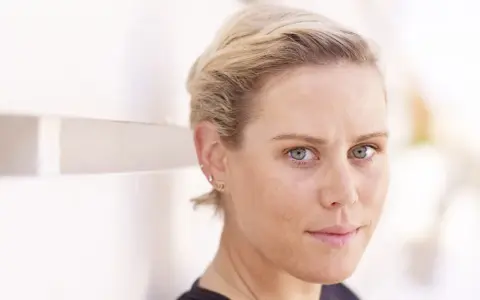 Nahaufnahme von Tiffany Cromwell mit blonden Haaren und blauen Augen, die nachdenklich in die Kamera blickt.