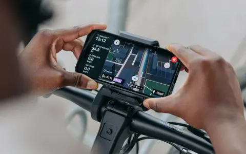 Hände halten Smartphone mit Bosch Flow App Navigation offline. Karte zeigt Route, Distanz und Geschwindigkeit.