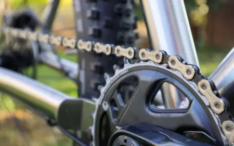 Nahaufnahme einer Fahrradkette, die über ein Kettenblatt läuft. Die Kette zeigt deutliche Gebrauchsspuren, was auf die Shimano Ketten Unterschiede in Bezug auf Haltbarkeit und Leistung hinweist.
