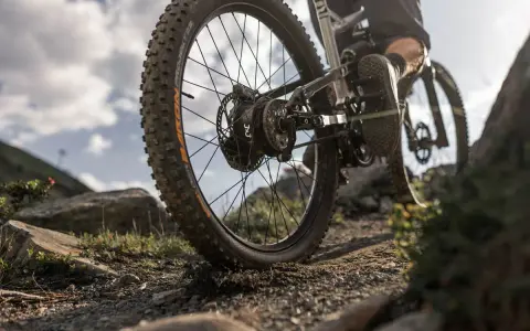 Detailaufnahme eines Mountainbikes mit 3x3 Schaltung auf steinigem Trail. Der breite Reifen meistert das Gelände.