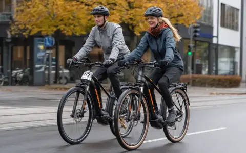 Ein Mann und eine Frau fahren mit ihren Pedelecs durch die Stadt. Was ist ein Pedelec? Ein Fahrrad mit elektrischer Unterstützung, das das Fahren erleichtert.