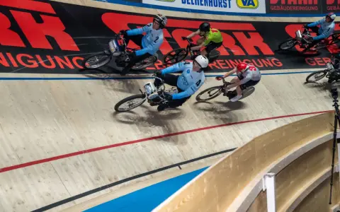 Radfahrer in blauen Trikots kämpfen auf der Bahn. Einer von ihnen könnte der beste Radfahrer der Welt sein, der alles gibt.