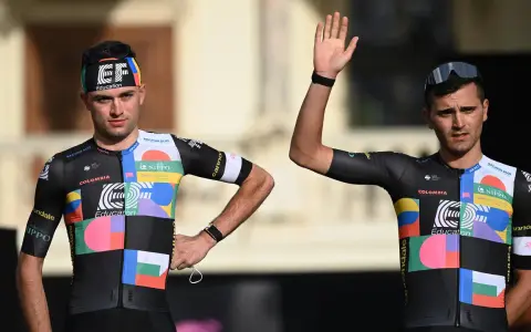 Zwei Radfahrer im bunten Trikot, bereit für den Giro d'Italia. Einer winkt lässig.