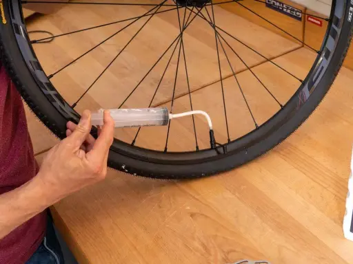 Mit einer Spritze wird Dichtmilch in den Tubeless Reifen gefüllt. So gelingt das tubeless reifen montieren.