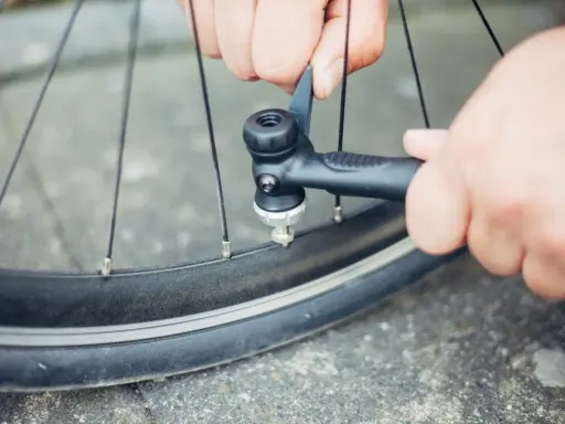 Hände pumpen mit einer Handpumpe Luft in ein Fahrradventil.