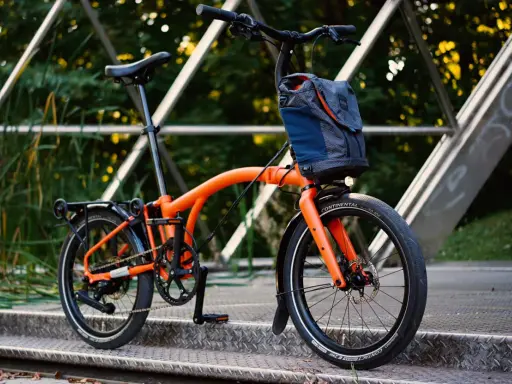 Orange Brompton Electric im Test auf einer Metallbrücke, bereit für die nächste Fahrt.