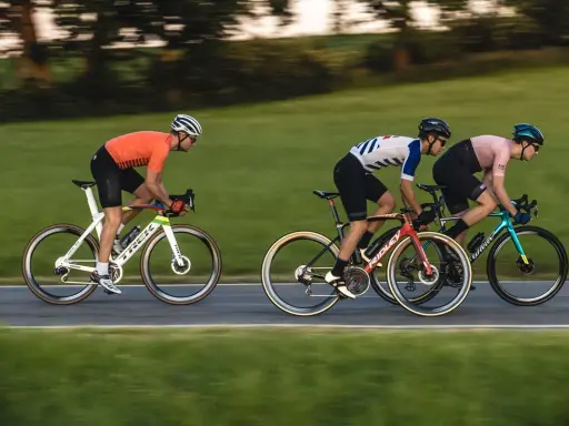 Drei Radfahrer auf schnellen Rennrädern, die an die Tour de France erinnern, fahren auf einer Straße.