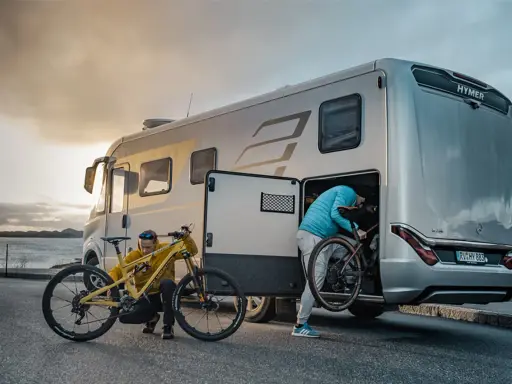 Zwei Personen laden Mountainbikes in einen Hymer Wohnwagen. Perfekt für Abenteuer mit dem e-bike wohnwagen.