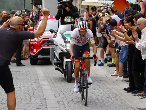 Giulio Ciccone fährt auf seinem Rennrad durch eine Gasse, umgeben von jubelnden Zuschauern und Motorrädern.