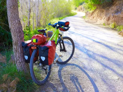 Ein grünes Trekkingrad mit roten Packtaschen steht am Wegesrand. Perfekt für Abenteuer, was ist ein Trekkingrad?