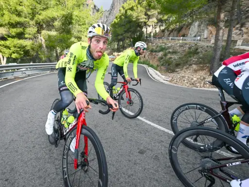 Jonas Rutsch zeigt Zunge auf dem Rennrad, während er auf einer kurvigen Bergstraße fährt.