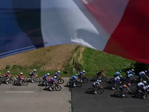 Radfahrer im Peloton, die französische Flagge weht im Wind. Ein spannender Moment am Tour de France Ende.