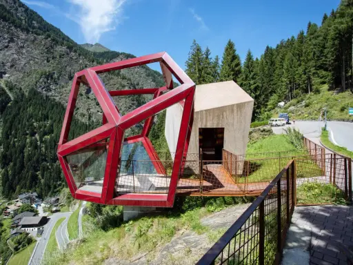 Moderne Architektur am Timmelsjoch. Ein Rennradfahrer genießt die Aussicht auf die Serpentinenstraße.