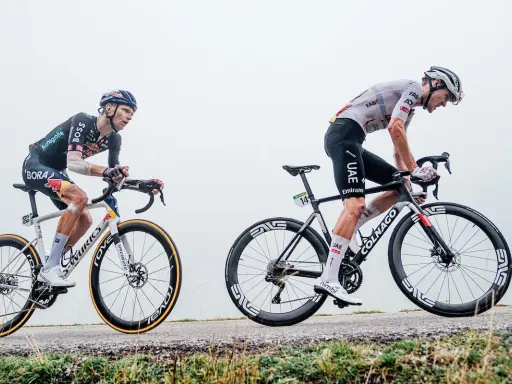 Pavel Sivakov kämpft sich auf seinem Rad einen nebligen Anstieg hinauf, während ein Konkurrent im UAE-Trikot neben ihm fährt.