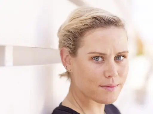 Nahaufnahme von Tiffany Cromwell mit blonden Haaren und blauen Augen, die nachdenklich in die Kamera blickt.