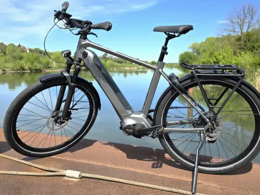 Graues E-Bike am Wasser. Die Preisentwicklung von E-Bikes ist spannend, dieses Modell bietet Komfort und Leistung.