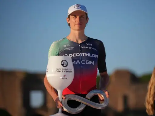 Felix Gall feiert seinen Sieg mit einem Pokal in Weinglasform und einer Infinity-Trophäe.
