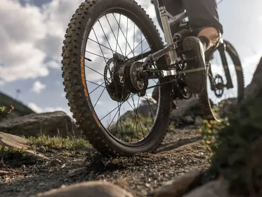 Detailaufnahme eines Mountainbikes mit 3x3 Schaltung auf steinigem Trail. Der breite Reifen meistert das Gelände.
