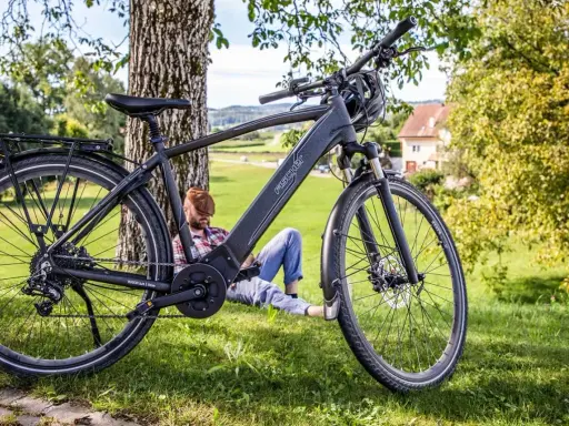 Fischer Viator 6.0i Test: Ein Mann entspannt sich im Schatten eines Baumes neben seinem E-Bike.