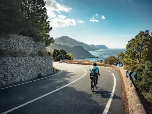 Rennradfahrer auf einer kurvigen Straße mit Blick auf das Meer und die Berge auf Mallorca.