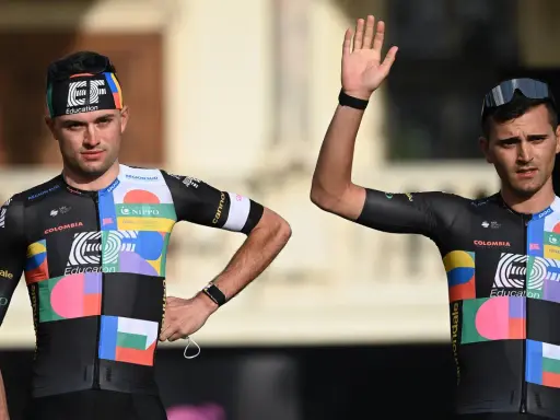 Zwei Radfahrer im bunten Trikot, bereit für den Giro d'Italia. Einer winkt lässig.
