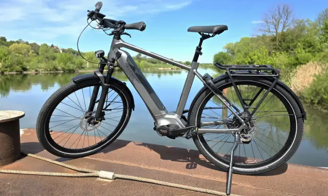 Graues E-Bike am Wasser. Die Preisentwicklung von E-Bikes ist spannend, dieses Modell bietet Komfort und Leistung.